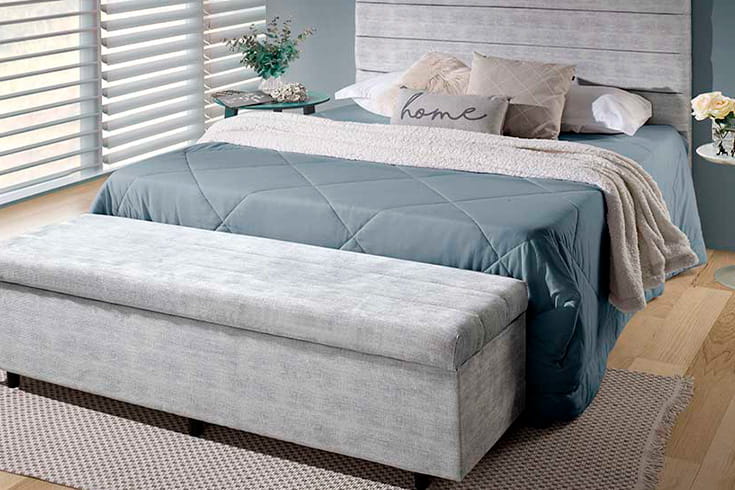 cama posta com roupa de cama em tons de azul e cinza
