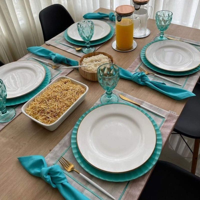 Mesa posta com jogo americano bege com pratos verde água