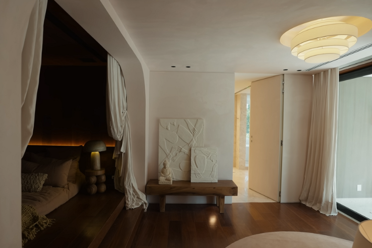 Quarto principal, com cortinas na cama de chão e quadros de gesso na mesa de cabeceira.
