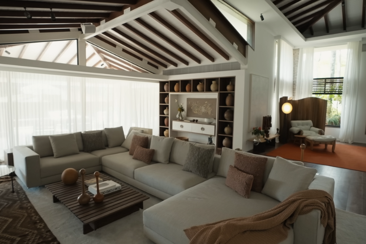 Sala de estar grande com sofá claro modular/em U com diversos vasos de tons terrosos no ambiente.
